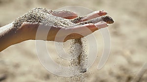 The macro snapshot of hand with sand strewed to fingers.