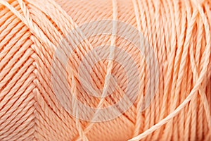 Macro texture of bright coral silk thread, close-up, copy space. Macro Photography of a coil with threads. Sewing