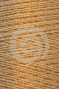 The macro texture of orange cotton thread on bobbin.