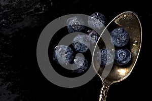 Macro Top View Image of Antique Spoon with Wet Blueberries on Dark Background