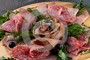 Macro view assorted sliced delicious meat mix as salami, bacon and ham with parsley and olives on a wooden cutting board