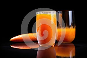 macro view of a carrot cut in half placed near a juice glass