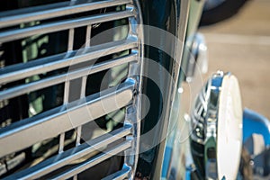 Macro view of chrome grill and headlamp on classic automobile