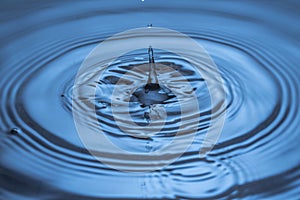 Macro view of falling drops on blue water surface isolated on background