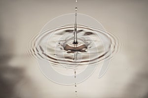 Macro view of falling drops on water surface  on brown background
