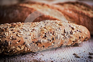 Macro view of fresh crunchy baguette bread with different seeds on the rustic wooden desk