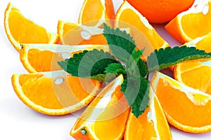 Macro view of orange with sections and green leaf of mint on white background