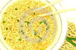 Macro view of plate of fastfood soup with green onion, chopsticks and raw ramen instant noodle uncooked