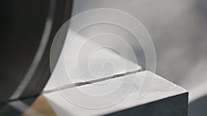 Macro view of working wheel of automatic circular saw cutting dark granite.