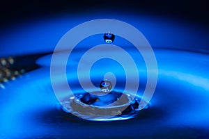 Macro water drop on a blue background and circles on it. Round water drop. splashes, spray, abstract shapes out of water