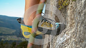 MACRO: Woman rock climbing up cliff steps off edge next to chalked up crimp grip