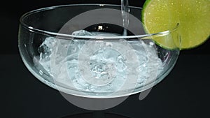 Macrography of a margarita being poured in a glass with lime slice. Comestible.
