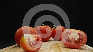 Macrography, slices of tomato placed on board with black background. Comestible.