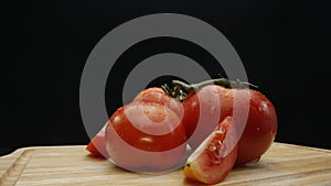 Macrography, slices of tomato placed on board with black background. Comestible.