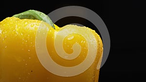 Macrography of a yellow bell pepper against a black background. Comestible.