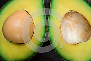 Macrophotography of a ripe avocado halves lying on a wooden background with copy space. One slice with core. Fresh food