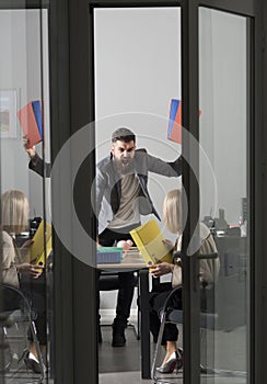 Mad crazy young businessman arguing with sad stressed businesswoman at work in office