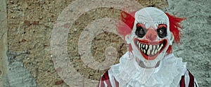 mad evil clown in front of a rustic house, banner