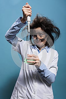 Mad foolish lab worker using pipet to mix experimental serum while grinning dreadful.