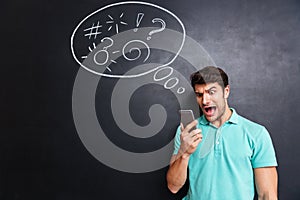 Mad furious young man using smartphone and shouting