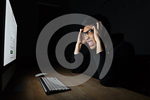 Mad irritated man working with computer in dark room