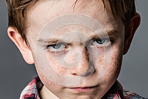 Mad little kid with furious blue eyes for childhood rebellion photo