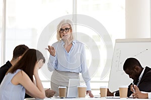 Mad mature businesswoman scolding employees for bad results