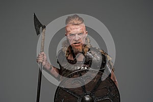 Mad redhead viking with shield and axe isolated on gray