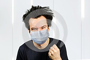 Mad young man wearing a protective face mask prevent virus infection or pollution with fist