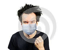 Mad young man wearing a protective face mask prevent virus infection or pollution with fist on white isolated background