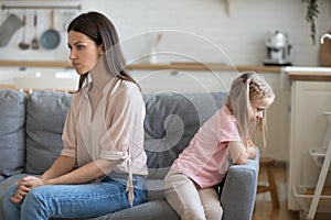 Mad young mom and little daughter sit separately after fight