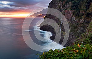 Madeira island - Dramatic sunrise over atlantic ocean with waterfall landscape from Miradouro do Veu da Noiva photo