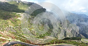 Madeira island, mountain road through the clouds with cliffs and beautifull nature surrounded on a sunny misty day in