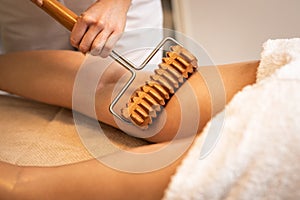 Close up of anticellulite massage with maderotherapy wooden rolling pin photo