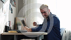 A madman home freelancer with glasses and yellow hair working at home, using a laptop. Sad and disappointment man