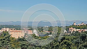 Madrid Cityscape with Distant Mountains, Panoramic view of Madrid's skyline with forest foreground and mountain