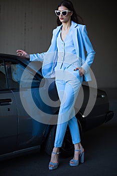 Mafia lady outside japonese car in the sea port. Fashion girl standing next to a retro sport car on the sun.