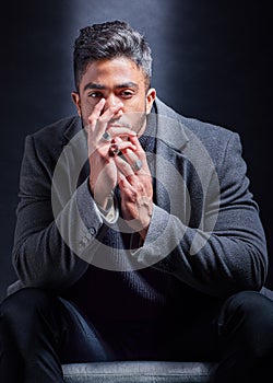 Mafia, portrait and man with fashion in chair on studio, dark background or businessman with power. Serious, person and