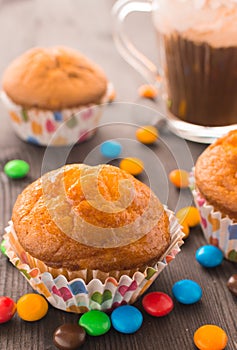 Mafins on a wooden table, beside scattered multi-colored tablets. Delicious dessert with a blurry background. Festive