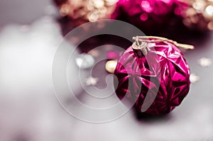 Magenta christmas ball on bokeh background of xmas ornaments.