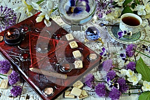 Magic book grimoire with runes, flowers, crystals and mystic objects on witch table