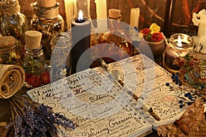 Magic book with spells, lavender bunch and black candle on witch table