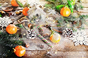 Magic Christmas background - vintage wood, candy cane, house, cinnamon, star anise, sweet mandarins with green leaves