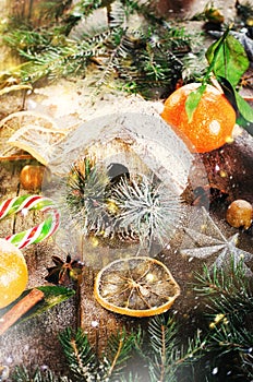 Magic Christmas background - vintage wood, candy cane, house, cinnamon, star anise, sweet mandarins with green leaves
