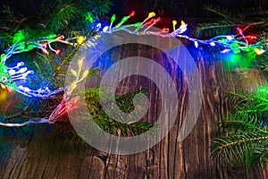 Magic Christmas garland with bright lights and fir tree branches on wooden background
