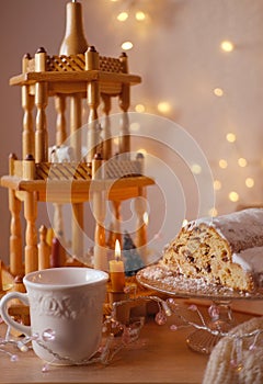 magic of Christmas with German Christmas bread-shaped cake stollen, Christmas wooden carousel with candles, mug of hot coffee, tea