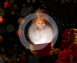 The magic of Christmas. Little girl opens a magical gift on the Christmas tree