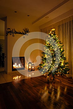 Magic Christmas night with glittering tree lights and burning candles in a fireplace, holiday season