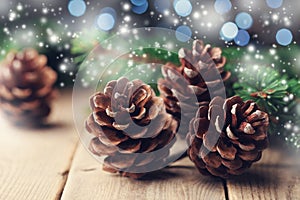 Magic composition with pine cones and fir tree branch on rustic wooden table. Christmas card. Snow effect.