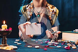 Magic and esotirism concept. The fortune teller shows an empty white tarot card. Mock up. Cartomancy and fortune telling photo